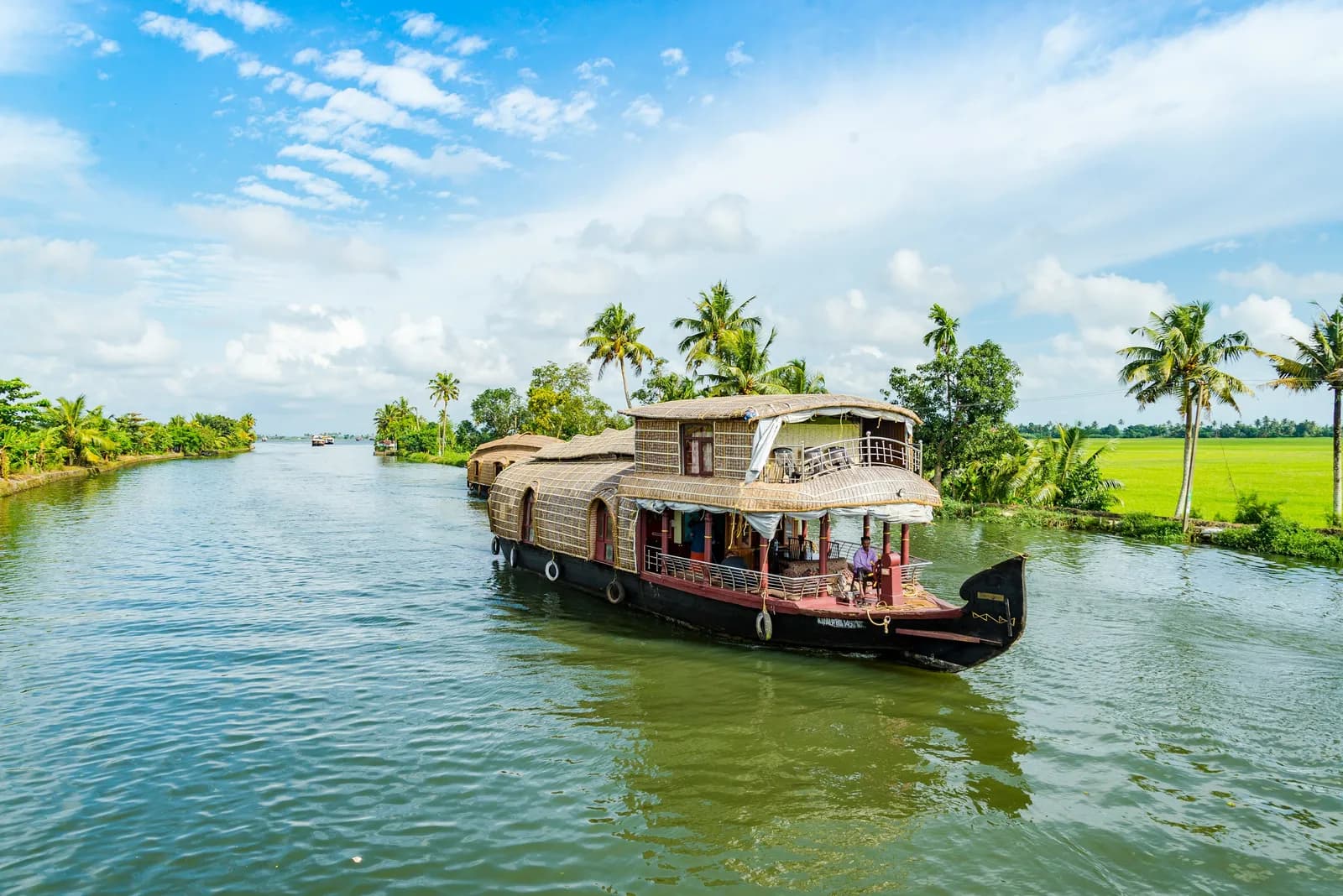 Traditional kettuvallam houseboat cruising a palm-lined canal in the Alleppey backwaters