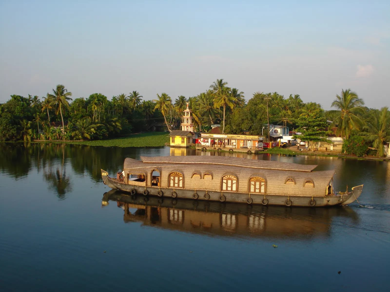 Traditional houseboat gliding across still water in Kuttanad, the rice bowl of Alleppey