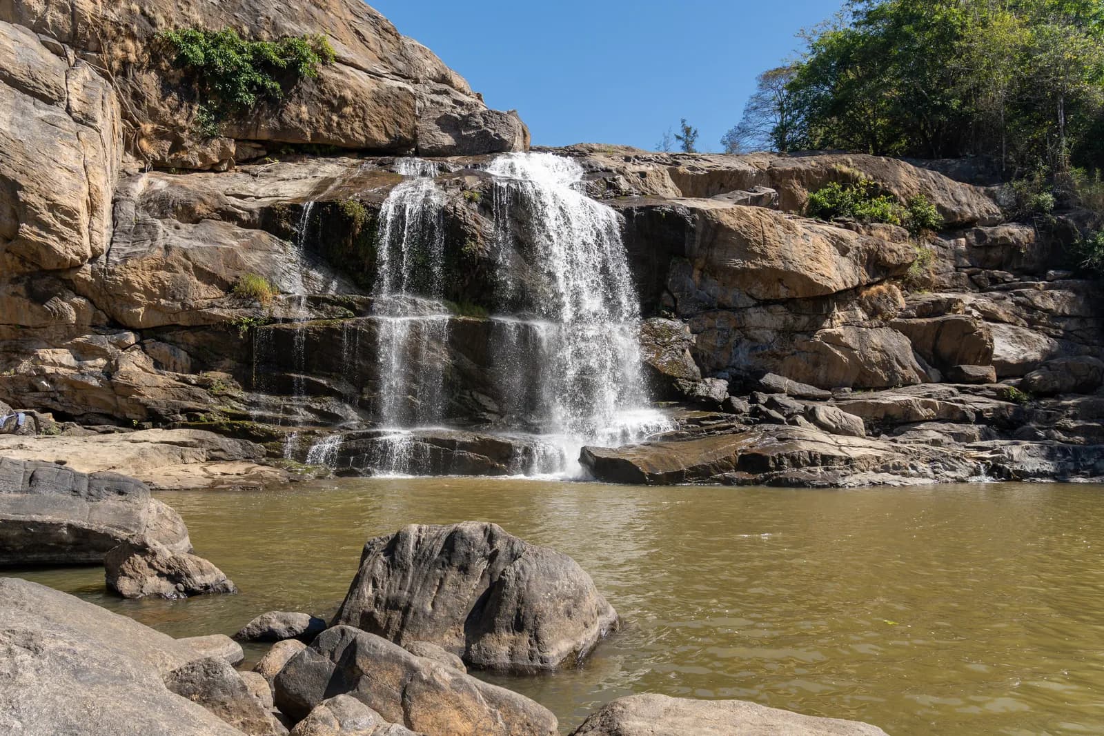 Pothupara waterfall cascading over rock ledges into a pool near Munnar