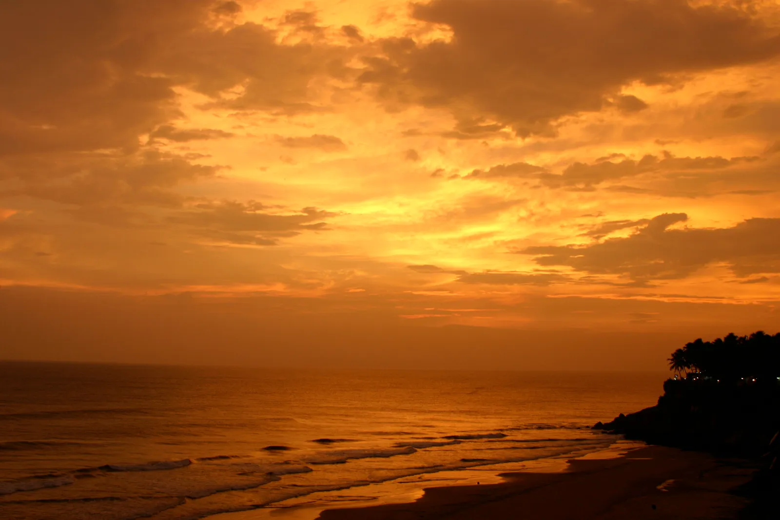 Golden sunset over the Arabian Sea beside the palm-topped cliffs of Varkala