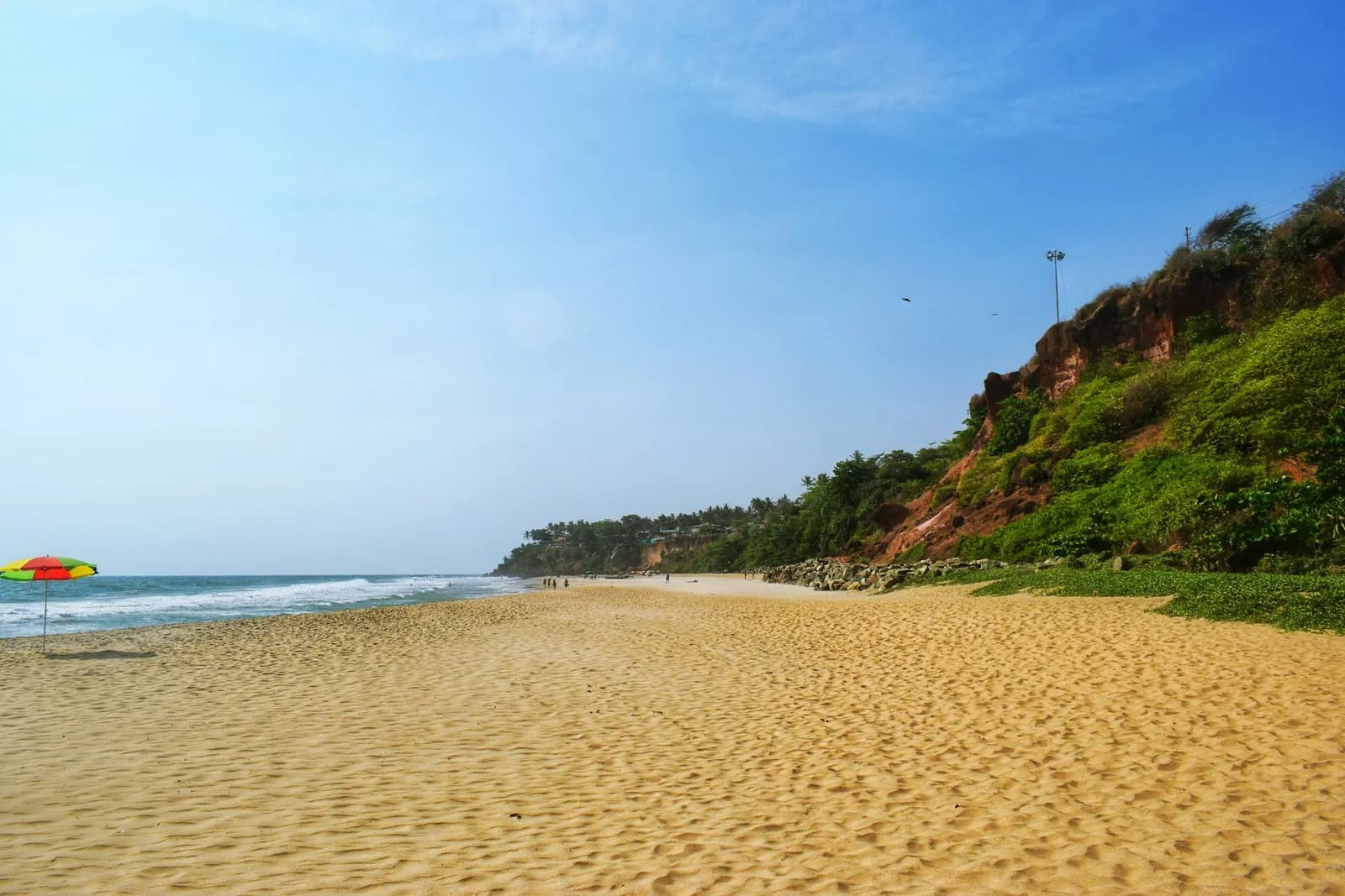 Golden sands of Varkala Beach stretching beneath its red cliffs